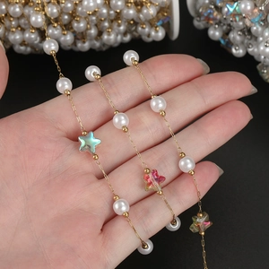 Detailed macro of 18K gold chain with white faux pearls and iridescent star beads