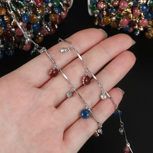 Dettaglio di catena in argento con ciondoli glitterati colorati per gioielli fai-da-te