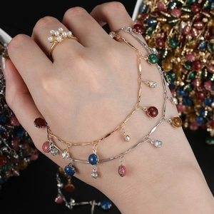 Anello con perla floreale e set di braccialetti con ciondoli colorati su mano femminile