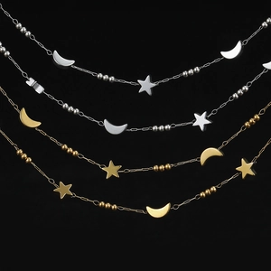 Detail of gold and silver chain with star and moon pendants on black background