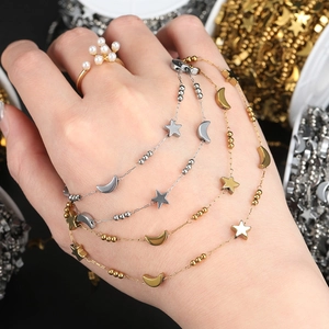 Macro detail of star and moon charms on gold and silver layered link bracelets