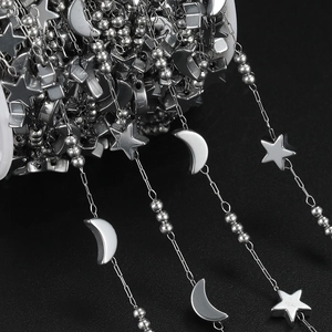 Macro view of stainless steel chain with star and moon pendants on a black surface