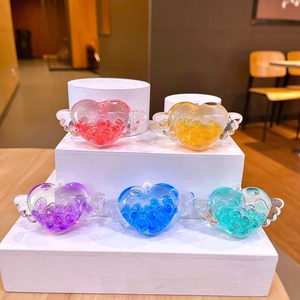 Dettaglio di cinque portachiavi a cuore alati colorati con sabbia glitterata su base