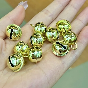 Polished gold metal pet bells on palm for DIY crafts and Christmas decorations