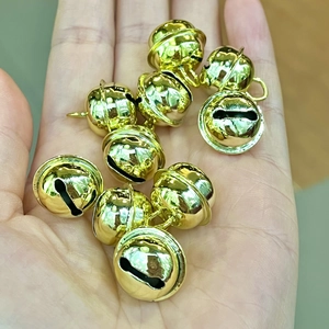Polished gold metal bells for DIY crafts and pets shown in a hand close-up