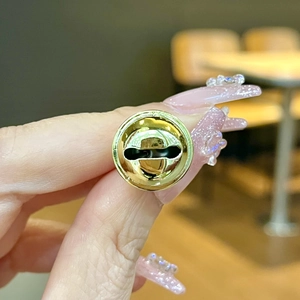 Macro shot of a shiny gold metal bell pendant with smooth polished finish and oval opening