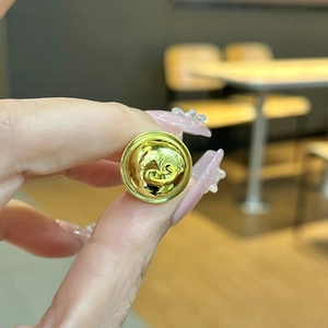 Close-up of a golden metal decorative button with spiral relief and grooved edges