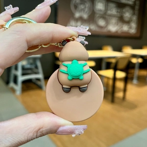 Vue détaillée d'un porte-clés Capybara rose avec tortue verte tenu à la main