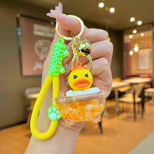 Detail of creative yellow duck keychain with silicone strap, bell, and green cat paw charm