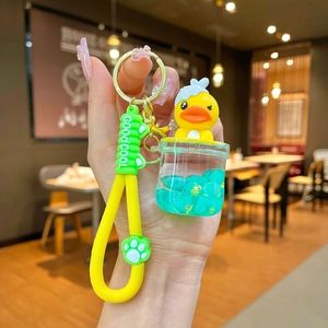 Detail of yellow duck keychain featuring a liquid charm with sequins and a silicone strap