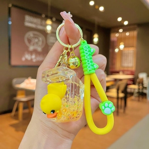 Detail of a milk bottle keychain with liquid sand, yellow duck, and a bell charm