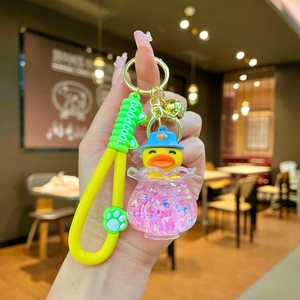 Detail of cartoon duck keychain with pink glitter sand bottle and yellow wrist strap