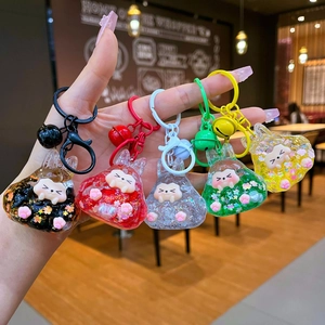 Hand holding colorful acrylic rabbit keychains with glitter and small bells in detail