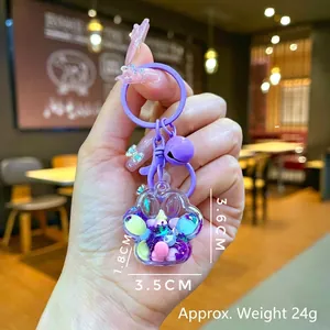 Detail of purple cat paw keychain with liquid sand, sequins, and bell, held in hand