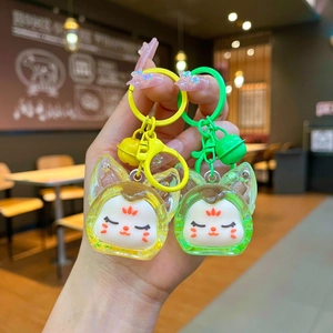 Gros plan de porte-clés chat en résine jaune et vert avec clochettes et accessoires