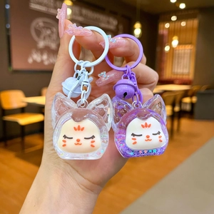 Détail de porte-clés chat en acrylique avec sable pailleté, clochette et anneau métal