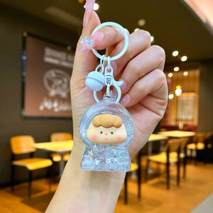 Close-up of cute cartoon doll keychain with liquid glitter and small white bell accessory