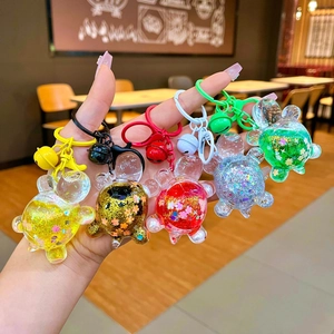 Close-up of five colorful cartoon turtle liquid quicksand keychains held in hand
