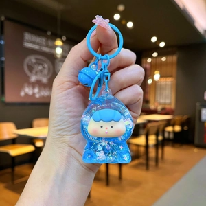 Blue glitter acrylic keychain with cute cartoon figure, bell, and star charm in hand