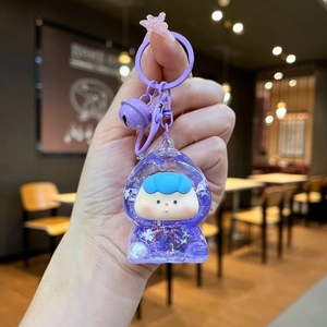 Close-up of a purple astronaut keychain with glitter sand and a small bell