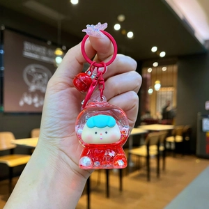 Detail of red astronaut liquid sand keychain with red bell and glittery star pendant