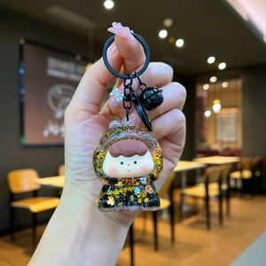 Detail of cute acrylic keychain with glitter character and small black bell accessory