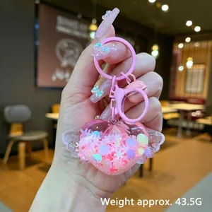Close-up of pink heart winged keychain showing glitter liquid sand and 7cm dimensions