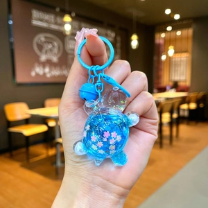 Detail of blue transparent turtle keychain with glitter and cherry blossom sequins inside