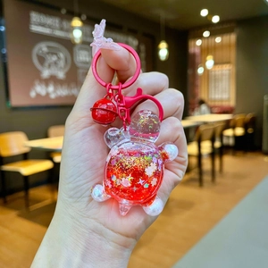 Detail of red bear liquid keychain with sparkling glitter stars and a red bell accessory