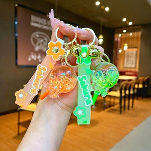 Detailed close-up of Sakura liquid glitter keychain with golden bell and silicone strap