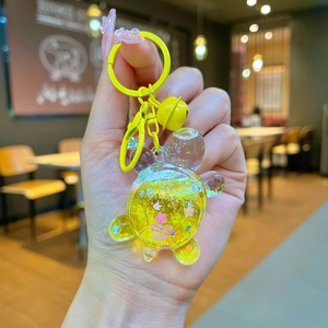 Detail view of a yellow bear keychain with floating liquid sequins and cherry blossoms