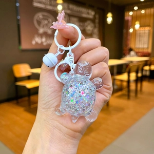 Close-up of cute cartoon turtle keychain with colorful glitter resin and a white bell