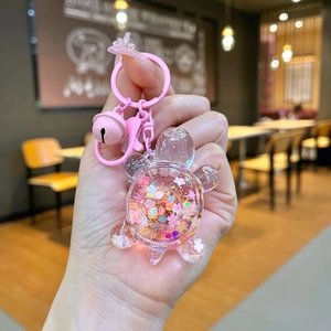 Close-up of pink turtle keychain with liquid glitter sand and a small pink bell