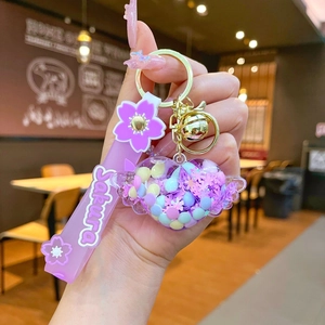 Detail of Sakura themed keychain with purple heart liquid sand charm and gold bell