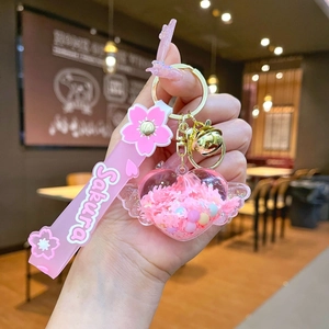 Close-up of heart-shaped liquid glitter keychain with Sakura wrist strap and bell