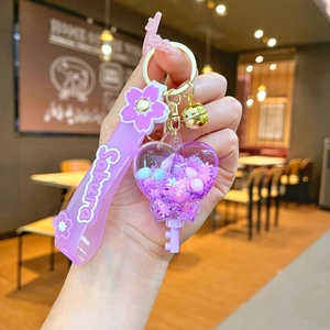 Detailed macro of a purple cherry blossom heart keychain with Sakura wrist strap and bell