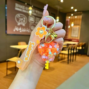 Close-up of heart-shaped Sakura liquid sand keychain with orange sequins and wrist strap