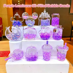 Pendentifs de sable liquide violet phosphorescent aux formes variées sur support blanc