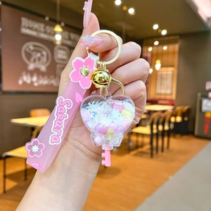 Close-up of pink cherry blossom acrylic heart keychain with liquid glitter and sakura strap