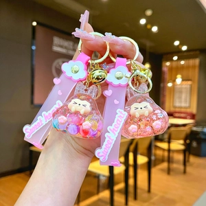 Détail d'un porte-clés lapin en résine rose avec clochette dorée et sangle assortie