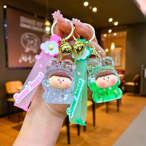 Detail view of pink and green liquid quicksand bear keychains with glitter and sequins