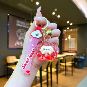 Detail of pink cartoon heart liquid sand keychain with golden bell and Sweet heart strap