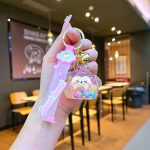 Detailed shot of pink cartoon cat liquid sand keychain with wrist strap and golden bell