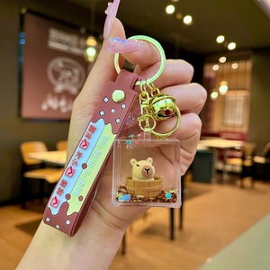 Detail of Capybara floating liquid keyring with brown silicone wrist strap and bell