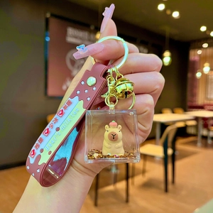 Detail of Capybara floating liquid keychain with golden bells and pink milk tea wristband