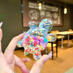 Macro detail of a liquid shaker turtle charm filled with colorful fruit slices and stars