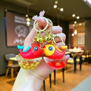 Close-up of a pair of koi fish keychains with fortune bags and golden bells for luck