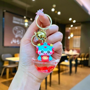 Detail of blue cartoon dragon keychain with red liquid sand inside a sycee charm
