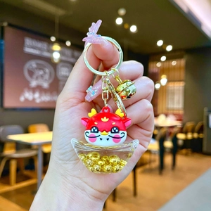 Detail of red cartoon dragon keychain with liquid sand gold ingot and golden bell charm