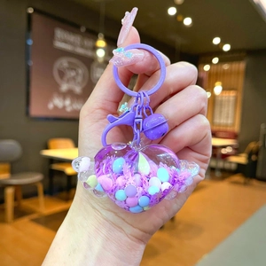 Close-up of purple heart wing keychain with quicksand and matching bell charms